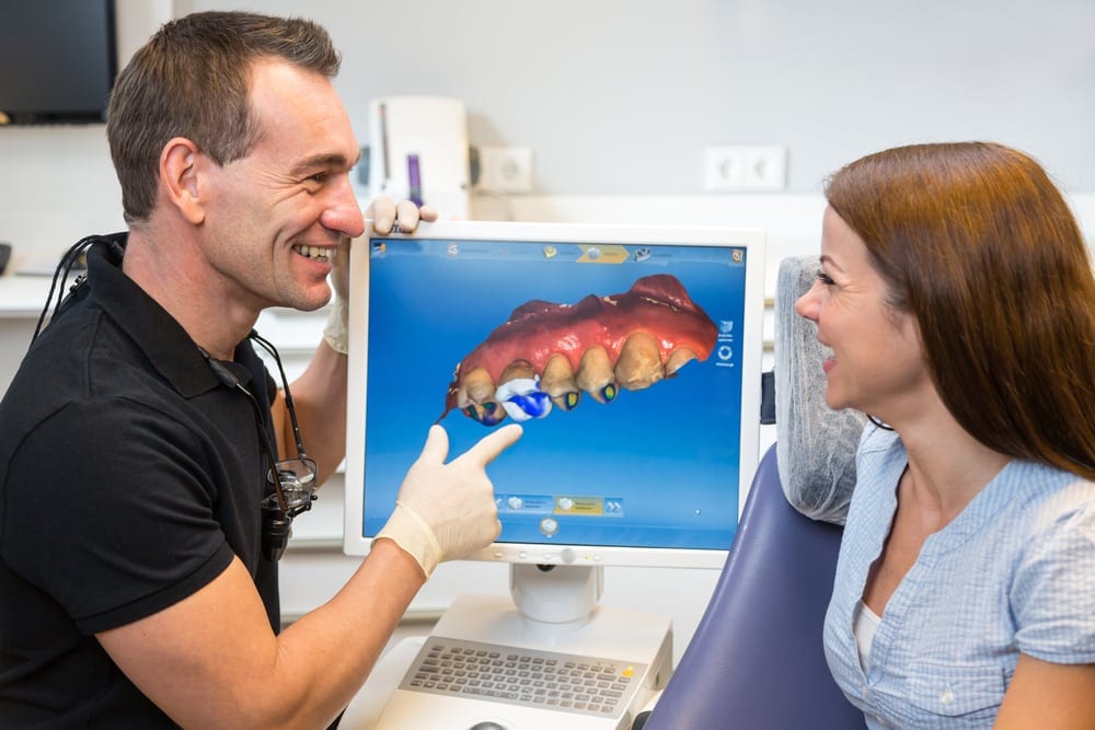 Dentist showing patient teeth view on camera