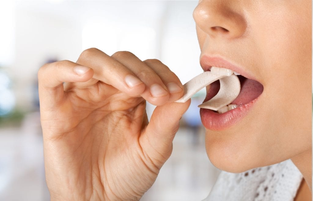 Woman placing a piece of chewing gum in her mouth