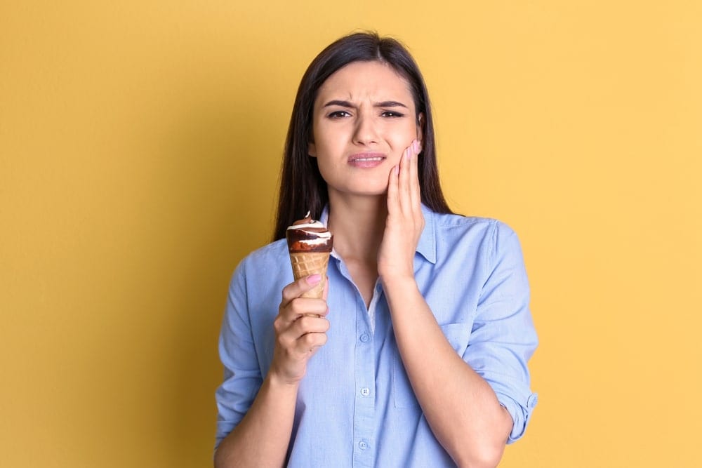 woman holding an ice cream cone with a pained expression