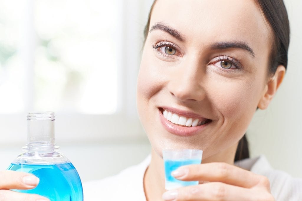 woman using mouthwash