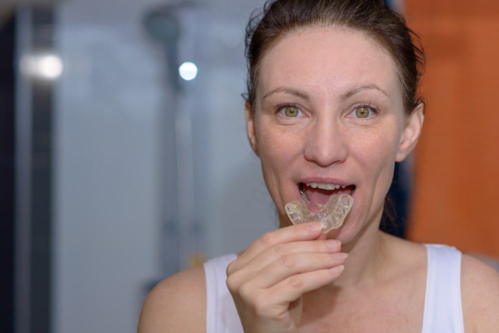 woman placing a dental night guard in her mouth