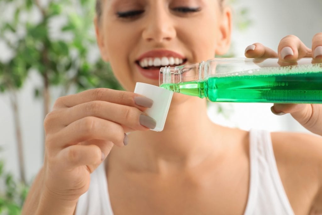 woman pouring mouthwash into a cup