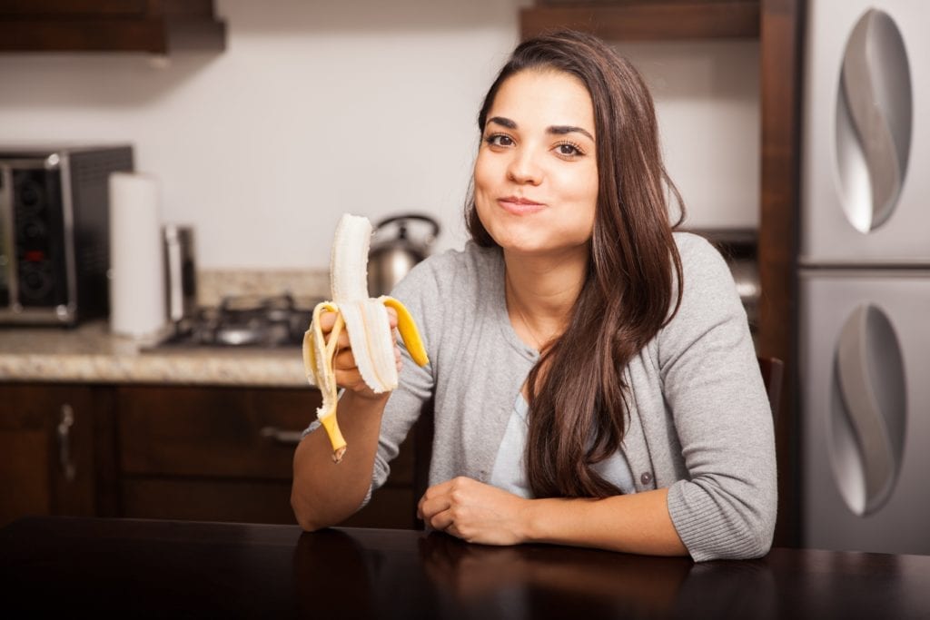 woman chewing on banana